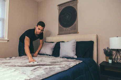 A man setting a bed in the room.
